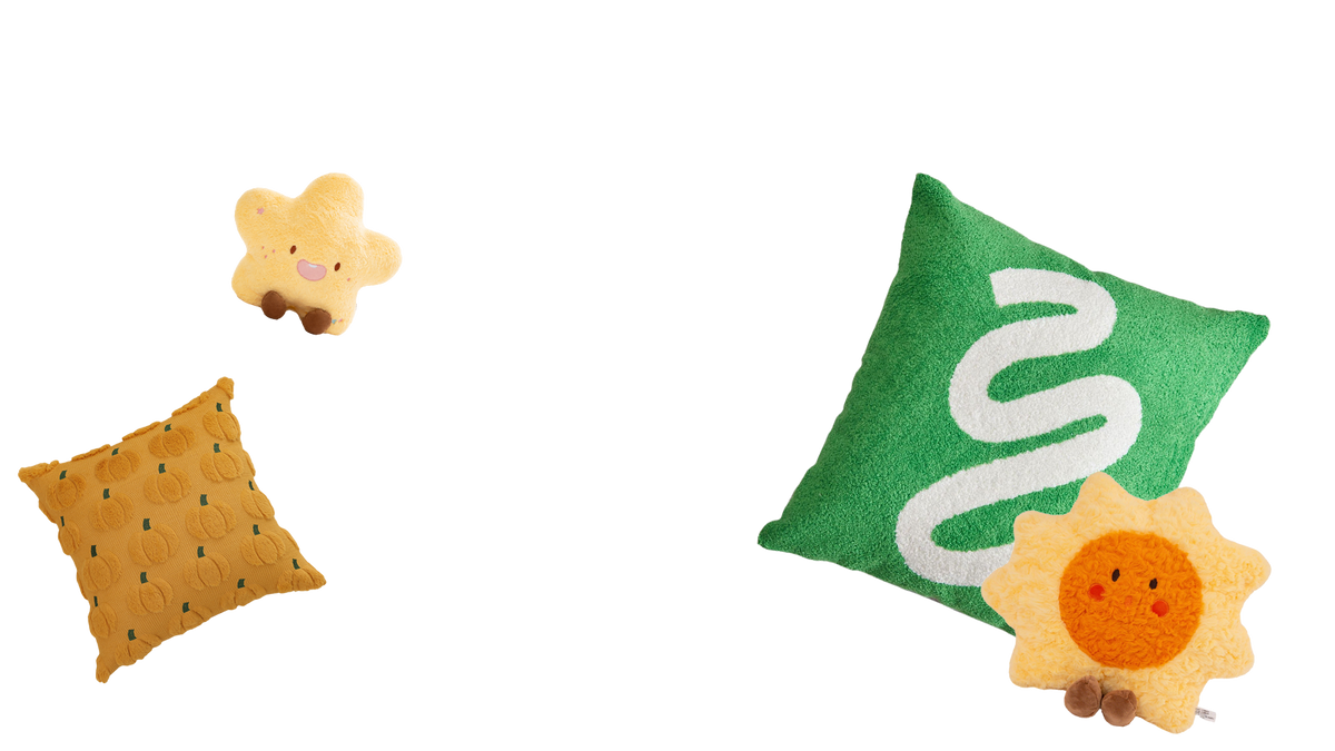 Assorted decorative cushions on a white background, including green and mustard square pillows, a smiling yellow star, and a cheerful sun-shaped cushion.